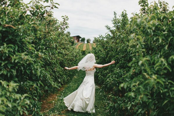 Sposa in abito bianco che corre lungo il sentiero