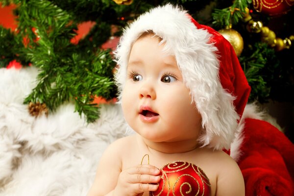 A child in a Santa Claus hat on the background of a Christmas tree