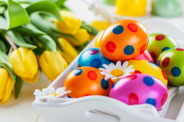 Colorful Easter eggs with tulips on the table