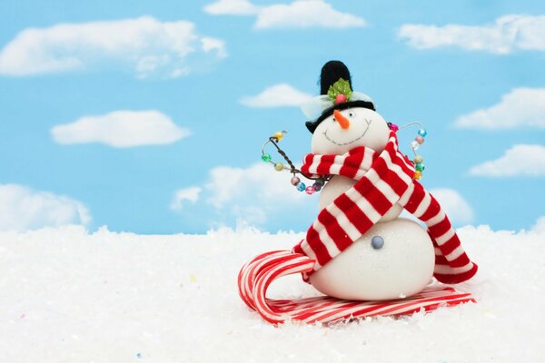 A snowman in a scarf against the sky