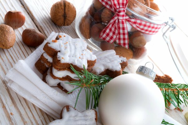 Weihnachtskekse mit weißer Schokoladenglasur auf einem Hintergrund aus Kugeln und Nüssen