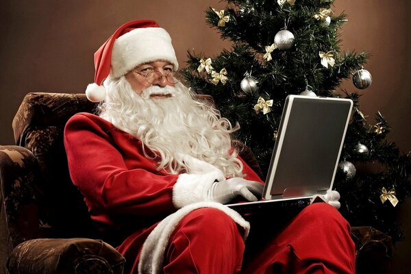 Święty Mikołaj w fotelu z laptopem