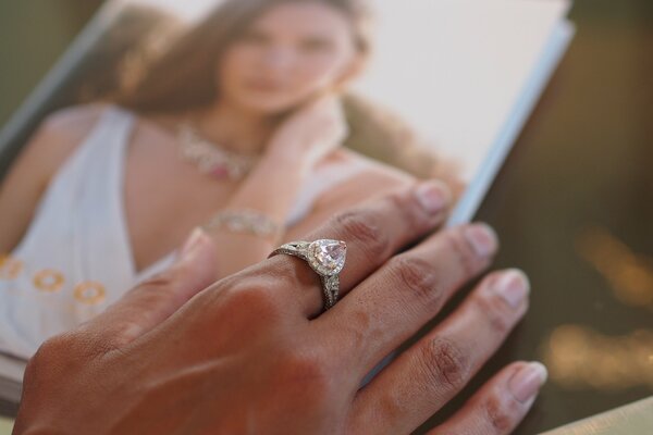 Weibliche Hand mit Ring über Hochzeitsfoto