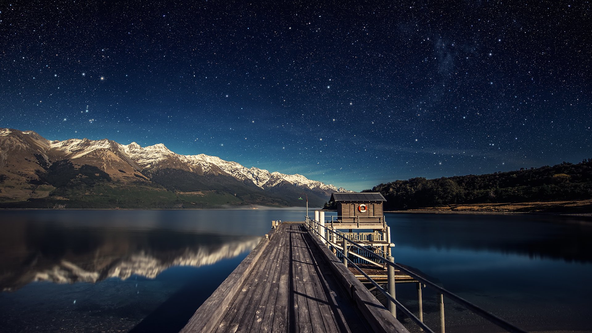 lago muelle montañas cielo estrellas