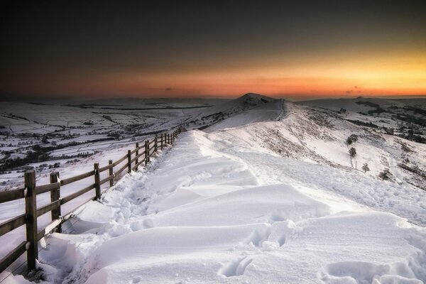 Footprints in the snow lead to the fence