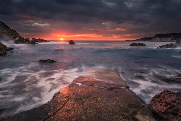 Tramonto sullo sfondo del mare sulla sporgenza solitaria della roccia