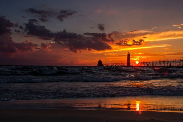 Lighthouse on the seashore in the rays of the setting sun