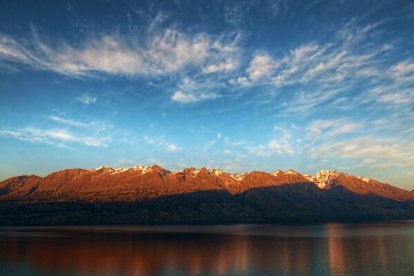 Paisaje de montaña en el reflejo de la superficie del agua con un cielo azul claro