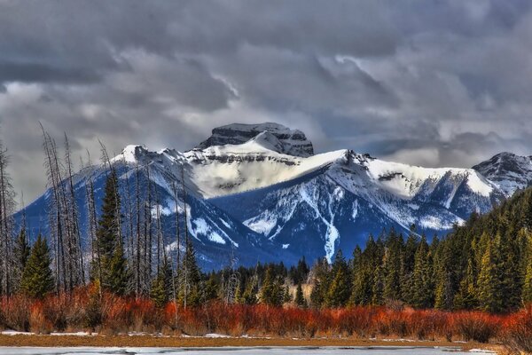 Landscape of snowy mountains against the background of an autumn forest