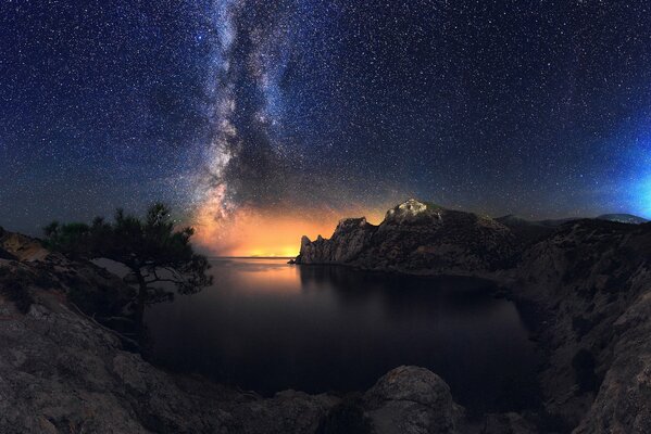 Belleza nocturna del cielo estrellado del mar de la costa rocosa