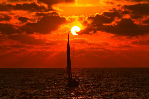 Yacht dans la mer sous le coucher du soleil écarlate