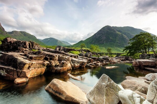 Paysage de montagnes forestières et de la rivière entourée de grosses pierres