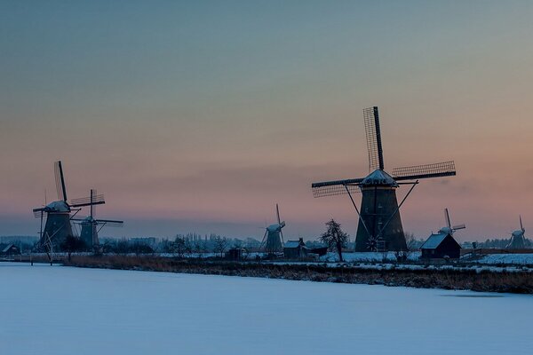 Snow-covered mills on the background of sunset