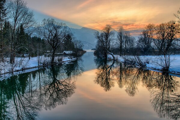 Der Winterfluss spiegelt das Glühen des Himmels wider