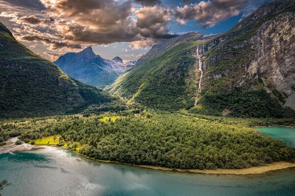 Panorama de montañas verdes y colinas con valle de bosque y superficie de agua