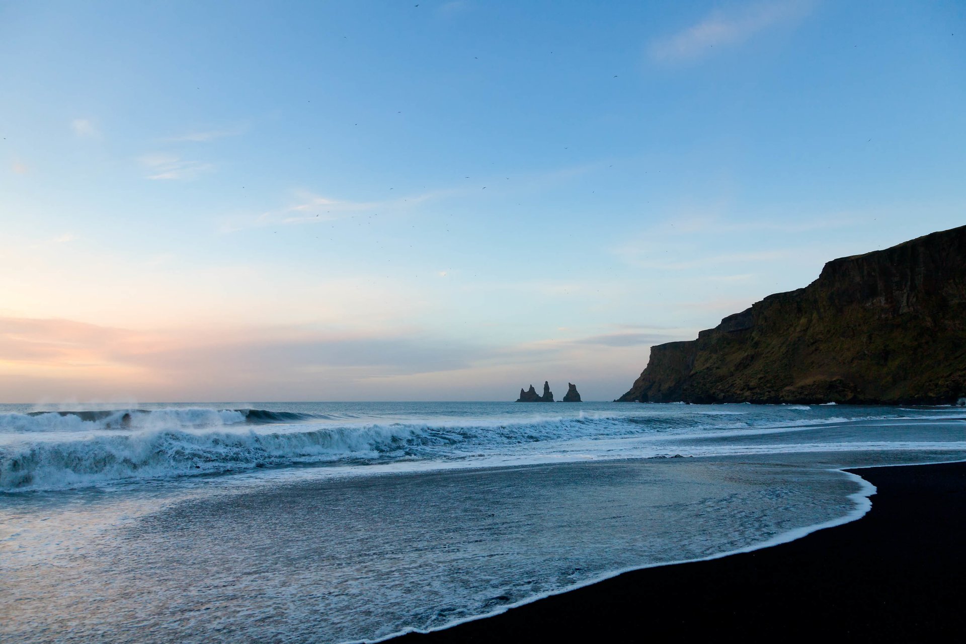 beach sand ocean water waves foam rock sky clouds birds horizon