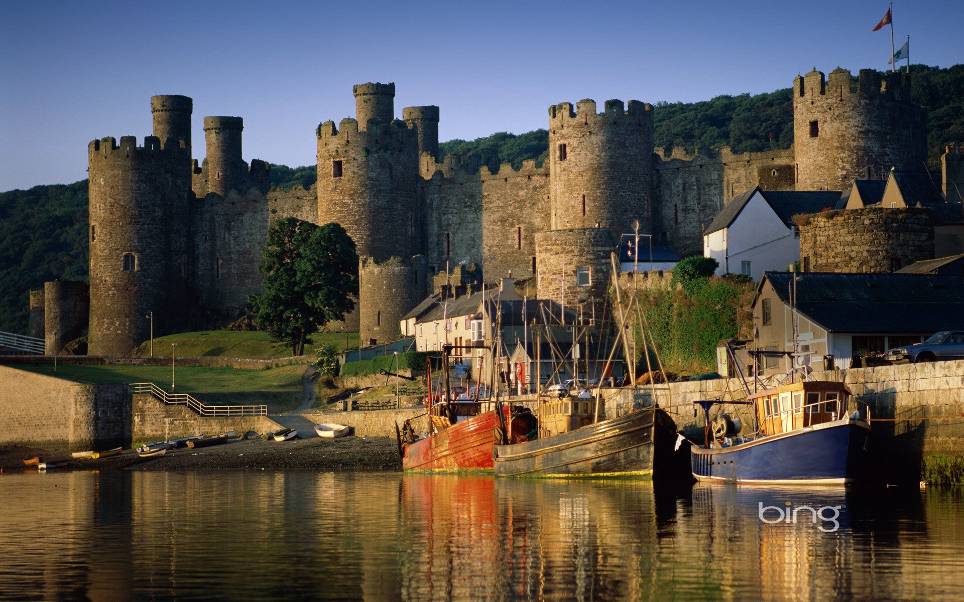 castle tower boat boat water bay house grass flag trees sky