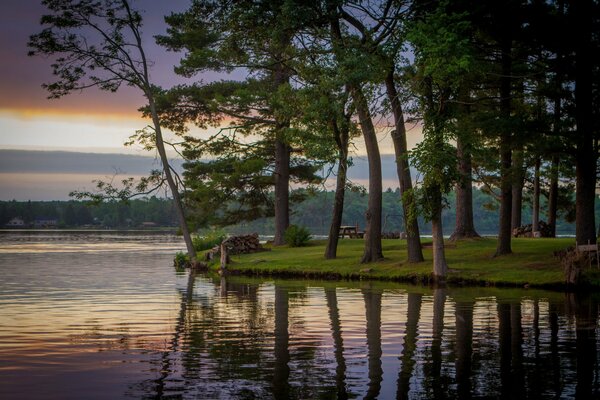 Lac avec des arbres sur la rive avec le reflet du ciel