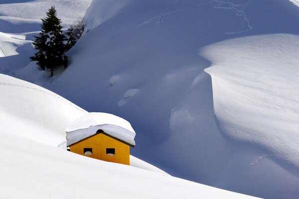 Gelbes Haus vor dem Hintergrund der schneebedeckten Berge