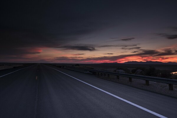 El camino en el fondo de la puesta de sol escarlata