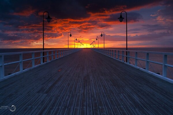 A long pier goes into the distance where you can see the sunset