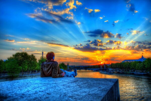 El hombre en la piedra durante la puesta de sol en París