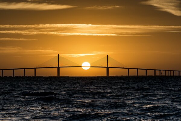 Orange sunset in the sea over the bridge