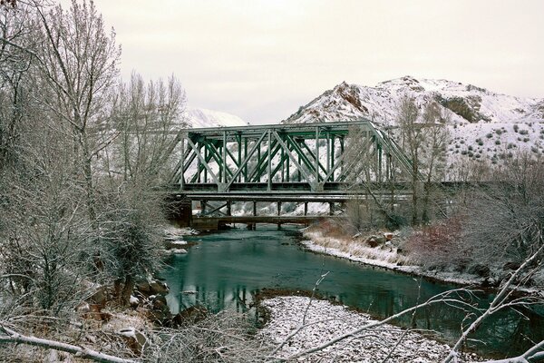 Winter image of the bridge against the background of mountains and trees