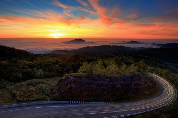 Puesta de sol sobre el largo camino y el bosque