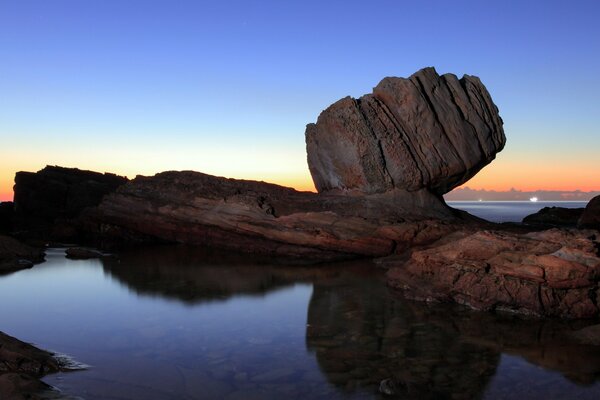 Reflection of rocks in the sea at sunset