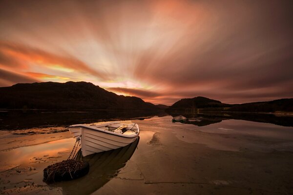 Лодка на берегу озера с закатом