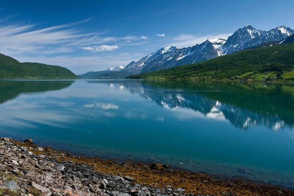Голубое небо и горы отражаются в озере