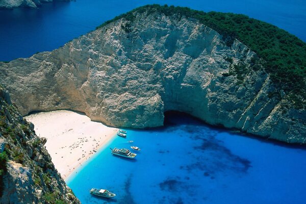 Plage avec des bateaux et des rochers avec de la verdure