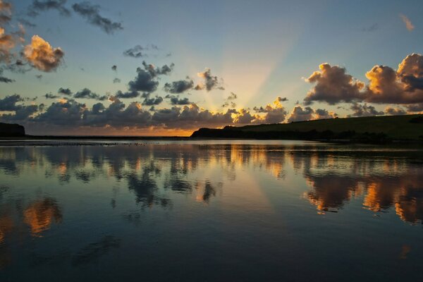 Sunrise on the river with the reflection of clouds in the water