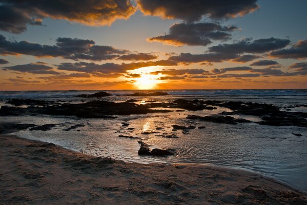 Das Meer und die sandige Küste vor dem Hintergrund des Sonnenuntergangs