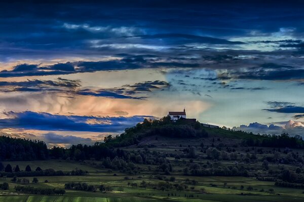 Iglesia de la tarde en la colina con el fondo del cielo al atardecer