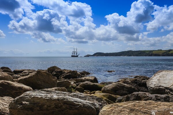 Velero en el mar. Vista desde la costa rocosa