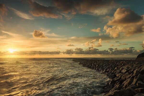 Schiuma di mare spiaggia rocciosa nuvole sole al tramonto