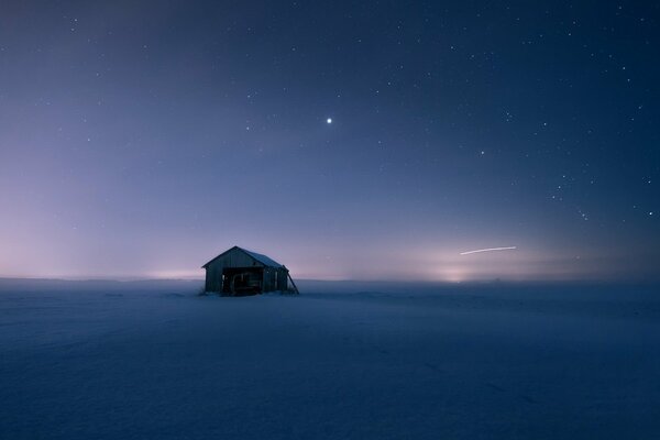 Samotny dom stoi na śnieżnym polu