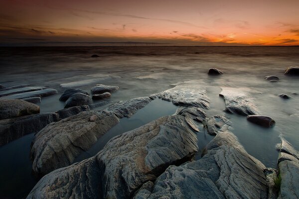 Rocky beach on the background of an orange sunset