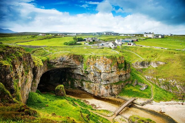 Colorido paisaje de Escocia. Ofrece vistas a pequeñas casas y montañas.. Verde brillante