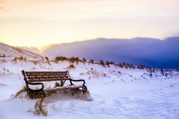 Eine Bank im Schnee und die Spuren um ihn herum