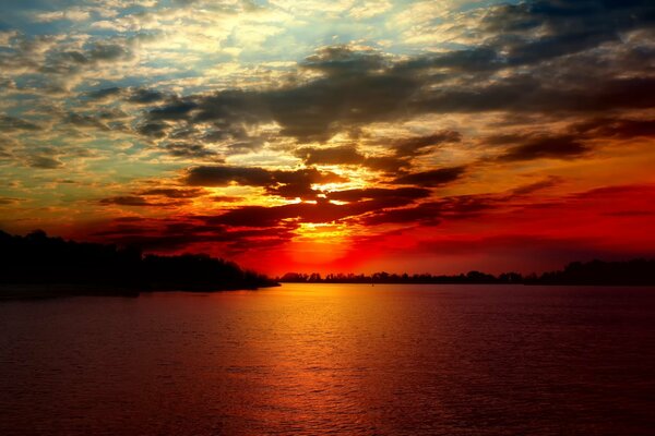 Il sole al tramonto illumina le incantevoli nuvole e l acqua