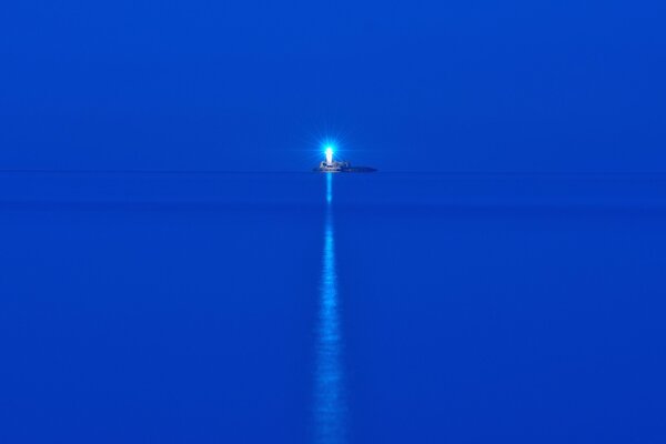 The blue sea in the night. Lighthouse on the island