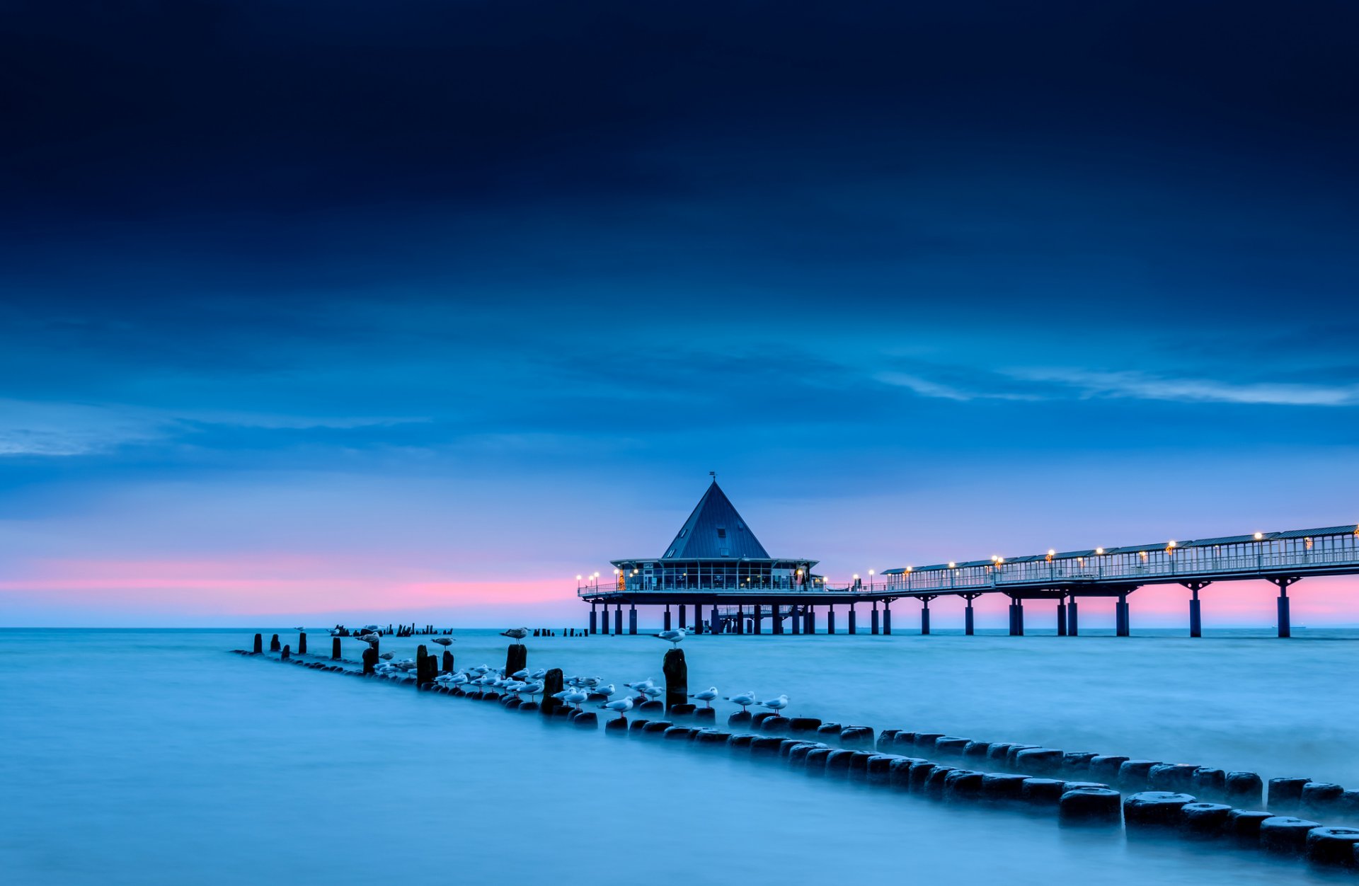 meer ufer stützen pier brücke lichter beleuchtung vögel möwen blau blau rosa himmel wolken morgen