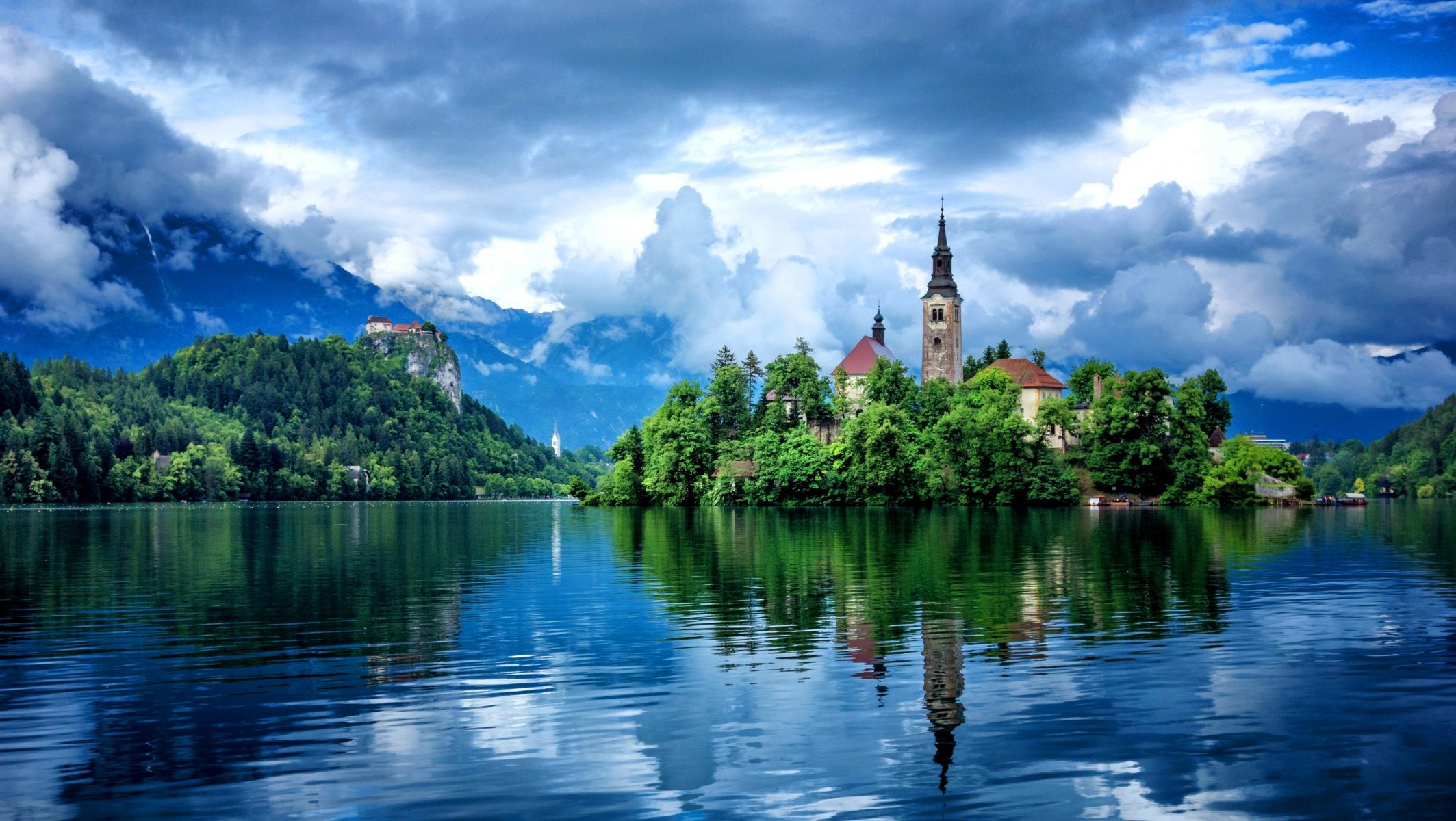 lago edificios reflejos montañas árboles cielo nubes