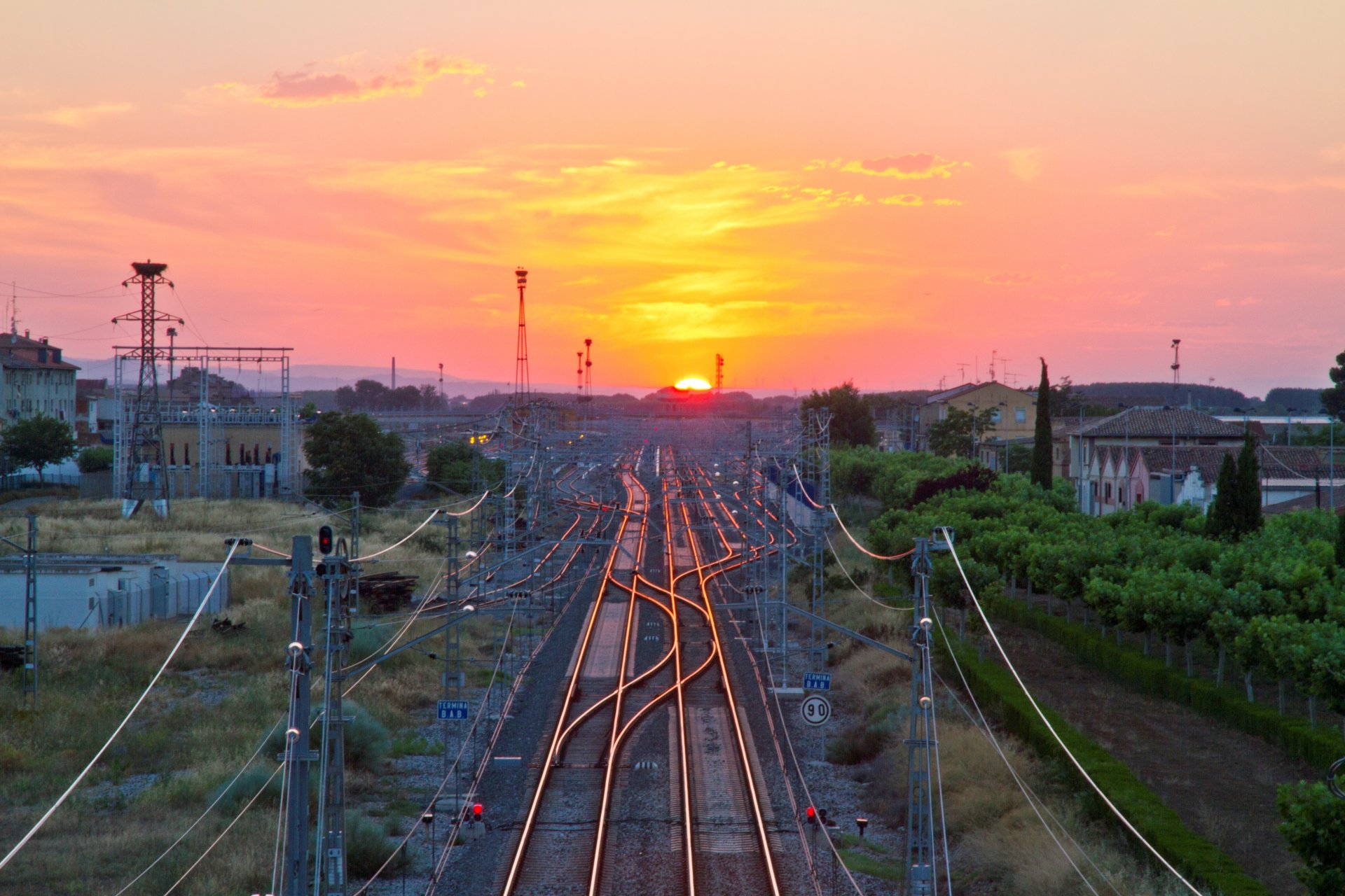 ferrocarril estación vías flechas edificios horizonte cielo sol puesta de sol