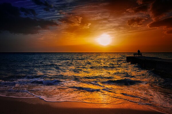 Pescatore su un molo vicino al mare al tramonto