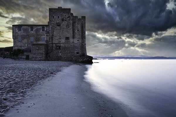 A gloomy tower on the shore of the sea at sunset