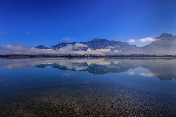 Der Himmel spiegelt sich im Forggensee wider